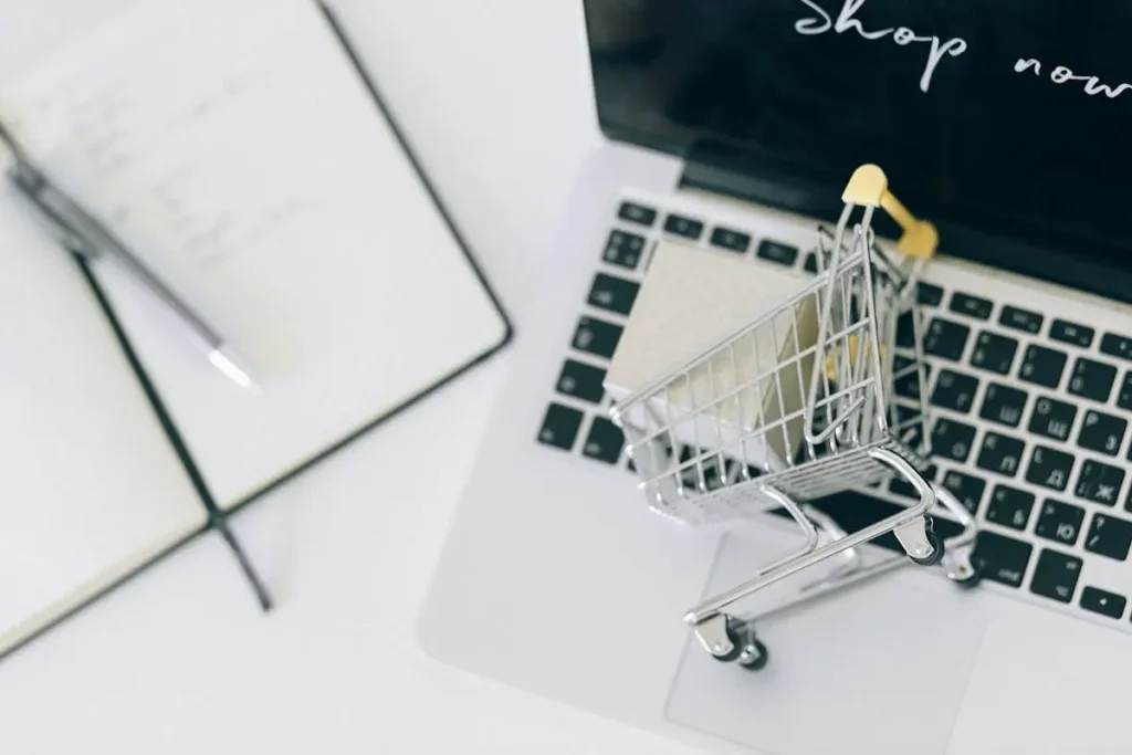 Laptop menampilkan grafik data bisnis di meja kerja dengan kotak paket, menggambarkan digitalisasi UMKM