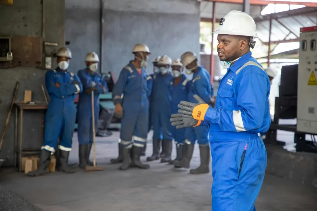 Sekelompok pekerja pabrik berpakaian safety sedang mengikuti sesi training kerja di dalam ruangan